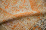 Distressed Oushak rug's textural pile, revealing knot heads, tangerine orange and ivory patterns.