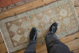 Distressed Oushak rug with even low pile showing coffee brown, ivory, green motifs and fringe.