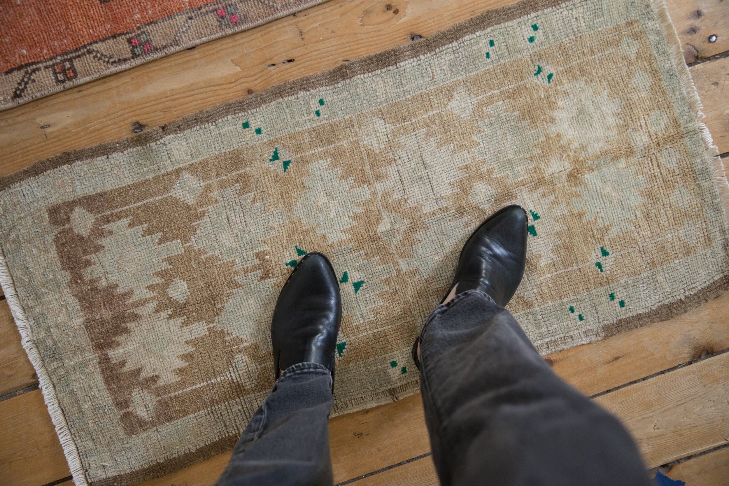 Distressed Oushak rug with even low pile showing coffee brown, ivory, green motifs and fringe.