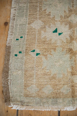 Distressed Oushak rug's side selvage, soft pile, and coffee brown, silver, green tones.