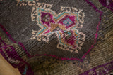 Distressed texture and vibrant purple, teal, charcoal quatrefoil pattern detail on vintage rug.
