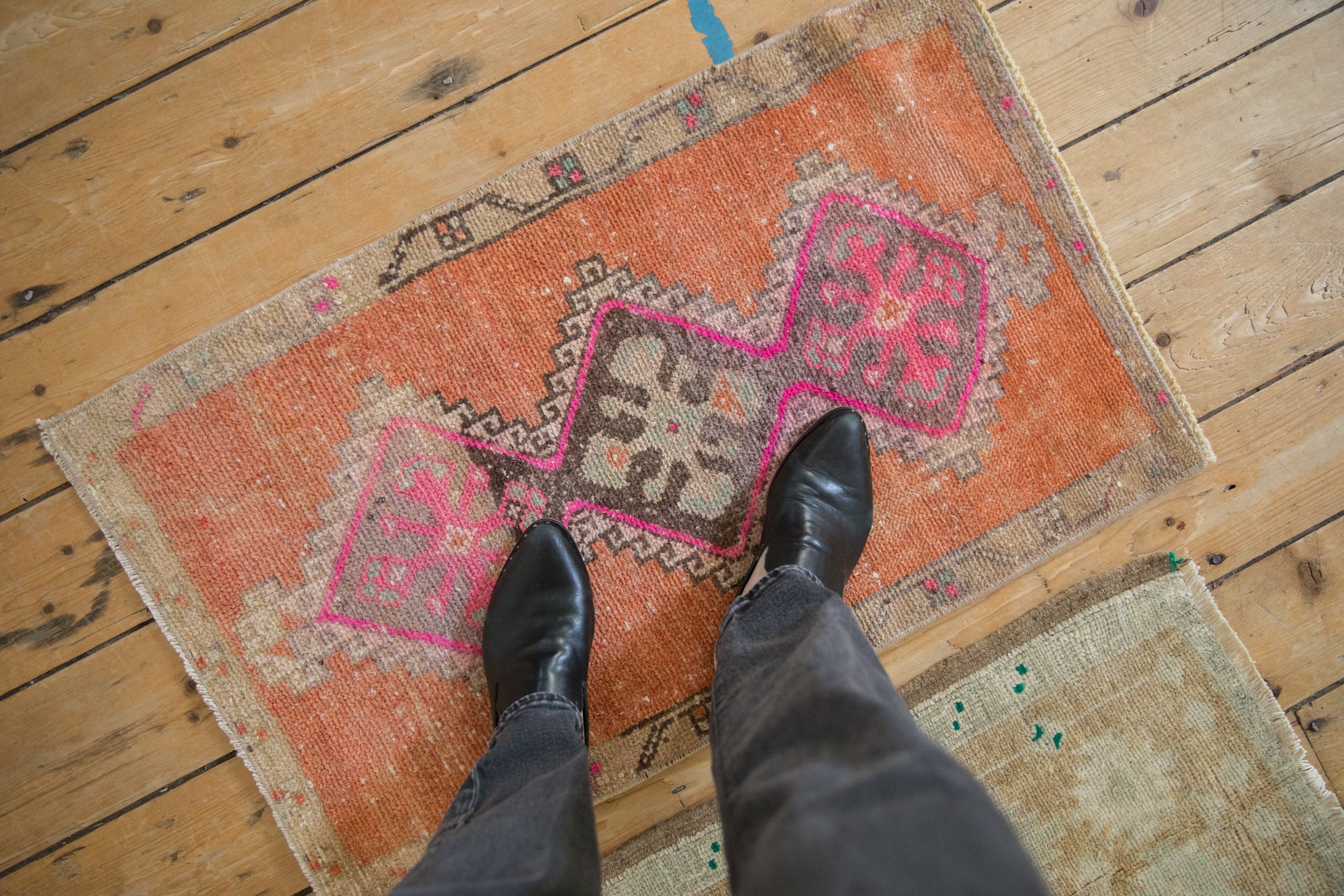 Vintage distressed Kars rug corner with terra cotta field, vibrant fuchsia geometric accents.
