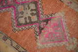 Distressed Kars rug detail: vibrant fuchsia outlining geometric floral motifs in terracotta.
