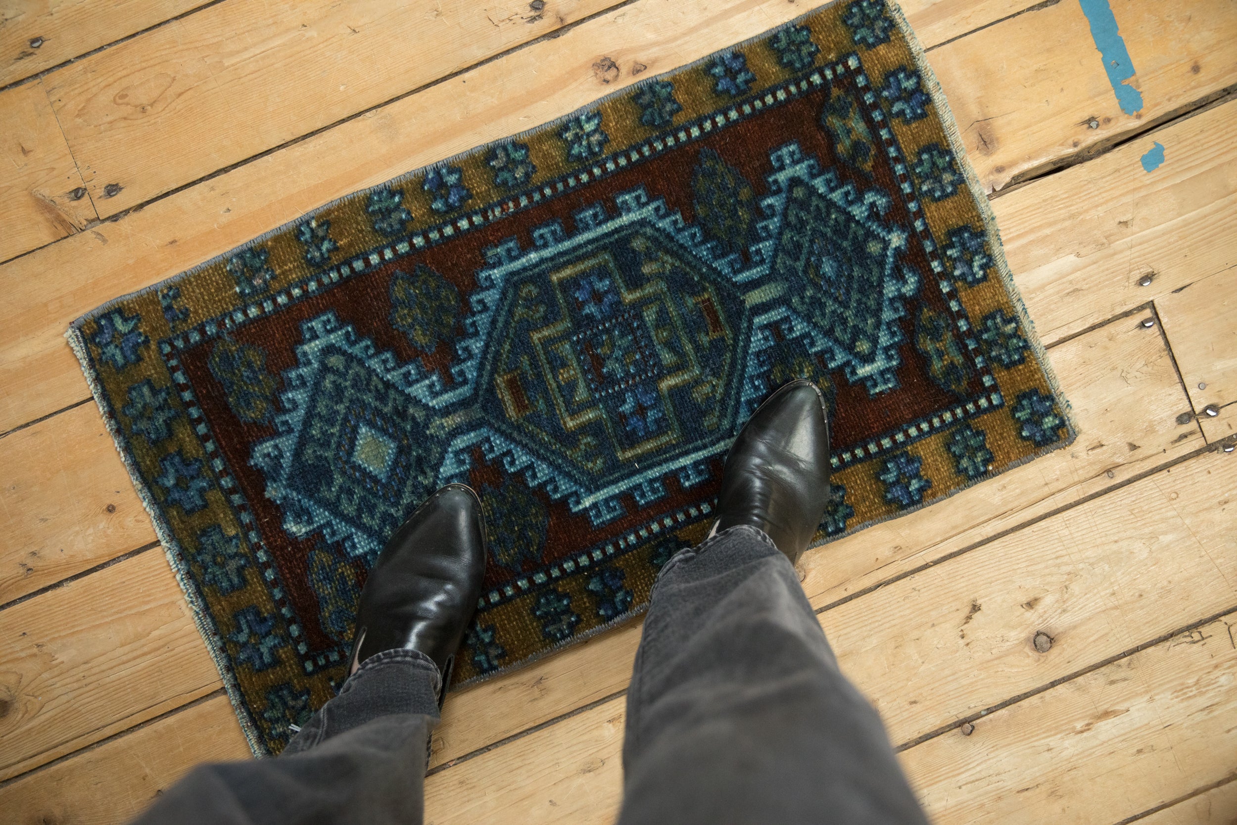 Distressed Kars rug mat with muted cobalt blue, purple, and ochre geometric patterns.