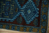 Close-up of the vintage Kars rug's distressed pile, geometric blossom border, and blue, ochre tones.
