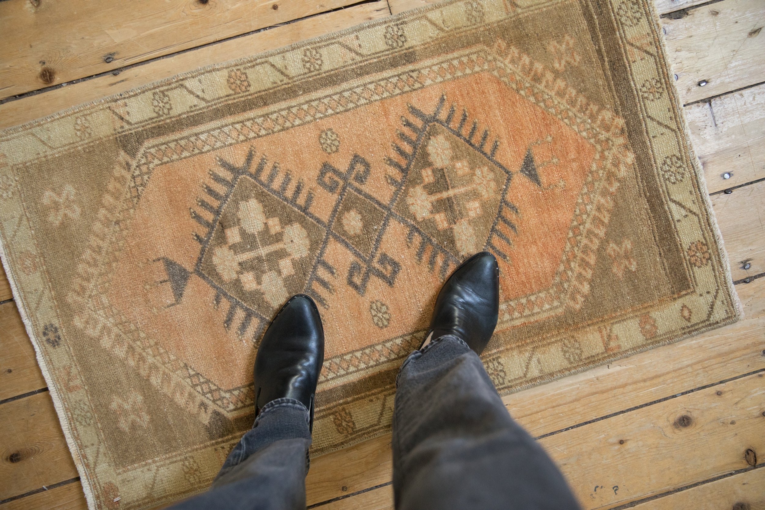 Distressed Oushak rug with muted peach and earth tones underfoot.