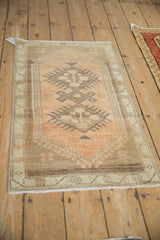 Distressed Oushak rug with softened diamond medallion and meandering vine border in muted tones.