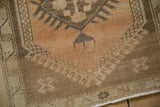 Distressed vintage Oushak rug corner featuring meandering vine border and machine-bound edge.