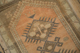 Vintage distressed Oushak rug's abrashed sandalwood field and meandering vine border detail.