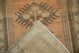 Distressed Oushak rug corner, revealing machine-bound edge, light reverse, and worn coffee brown pile.