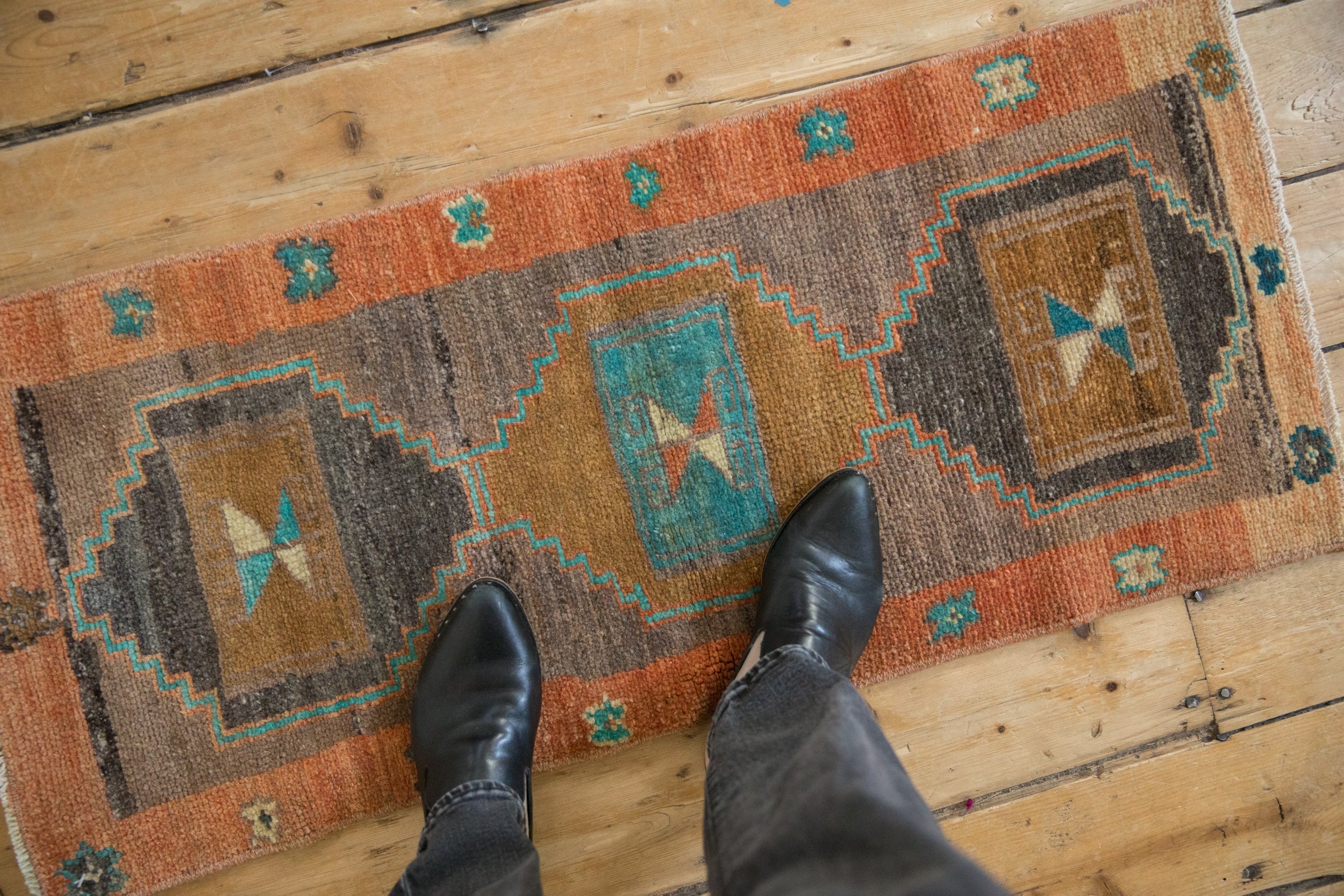 Distressed Kars runner with terra cotta, bronze, and turquoise geometric stepped pattern underfoot.