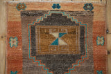 Close-up of vintage Kars rug's primitive stepped medallion, with bronze, terra cotta, and turquoise.