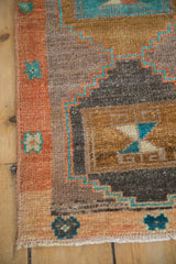 Vintage Kars rug's terra cotta border, turquoise geometric steps, and simplistic floral motifs.