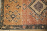 Corner of distressed Kars rug: abrashed sandalwood field, dark geometric patterns, bound edge.