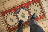 Distressed geometric medallion with turquoise pinwheel motif and brick red field.