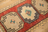 Distressed Kars rug section: geometric ivory medallion, speckled brick red field, zigzag border.