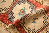 Textured pile of a folded distressed Kars rug with geometric medallion and turquoise pinwheel motif.