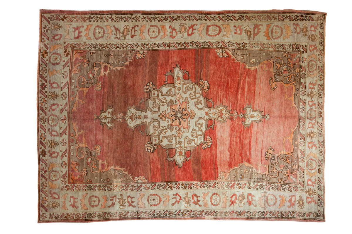 Distressed vintage Oushak carpet with central medallion, abrashed red field, 7' x 9'4".