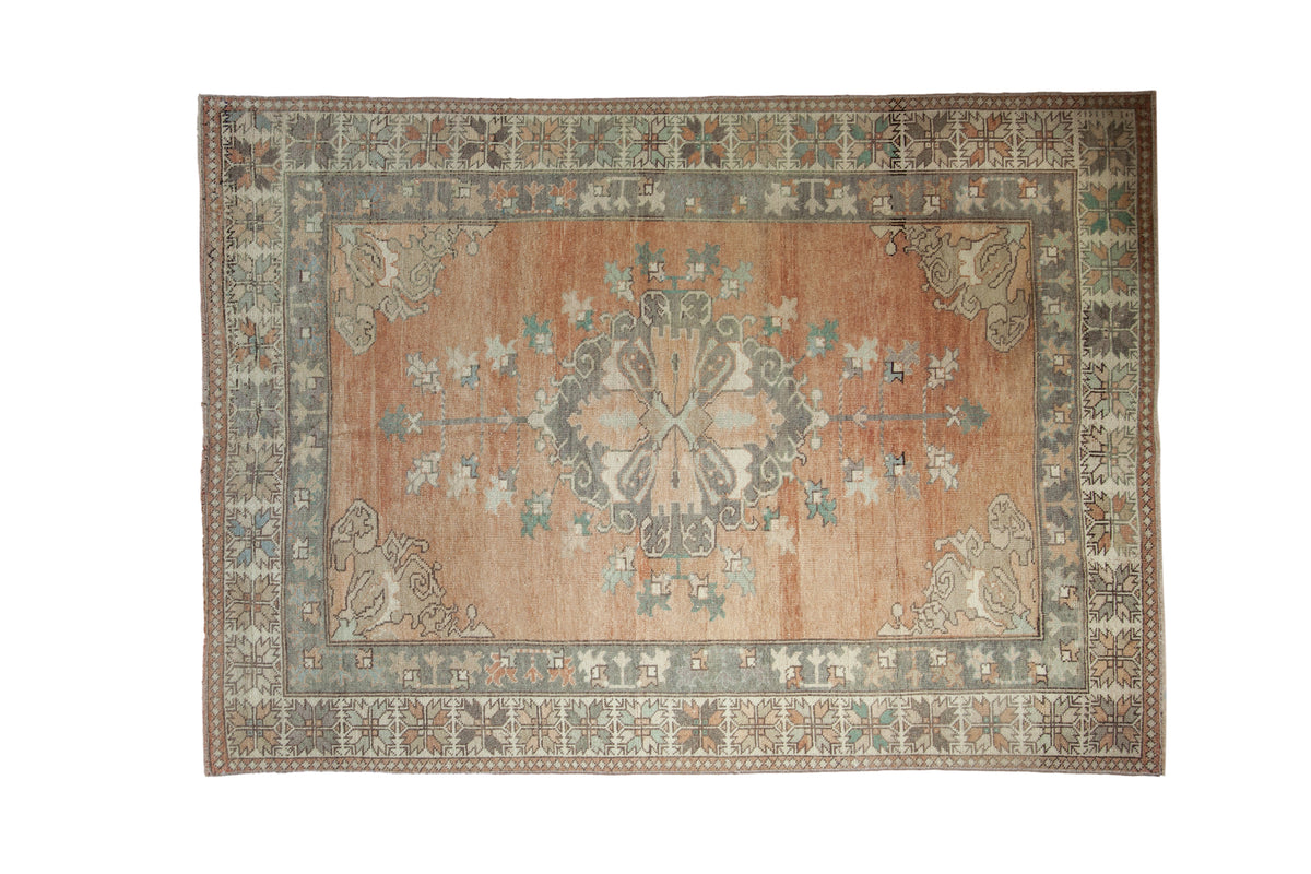 Distressed vintage Oushak rug, roundel medallion, rococo vines, in terracotta, beige, seafoam tones.