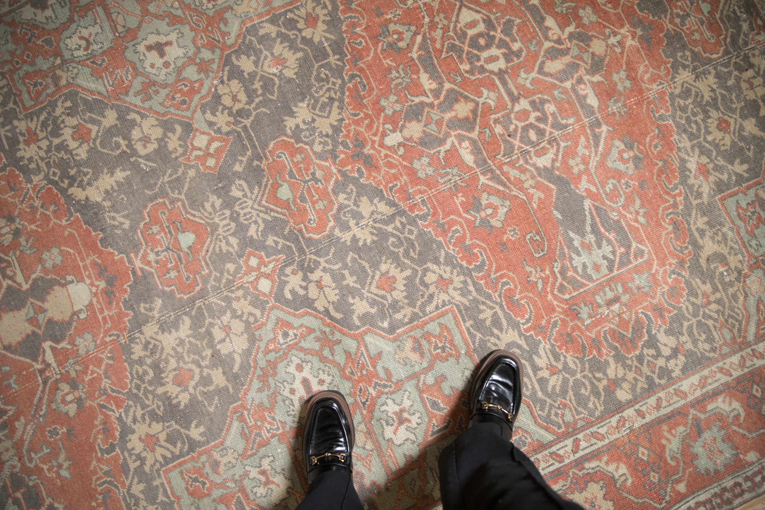 Distressed vintage Sparta rug detail, dusty terra cotta and grey curvilinear motifs, worn pile with feet.