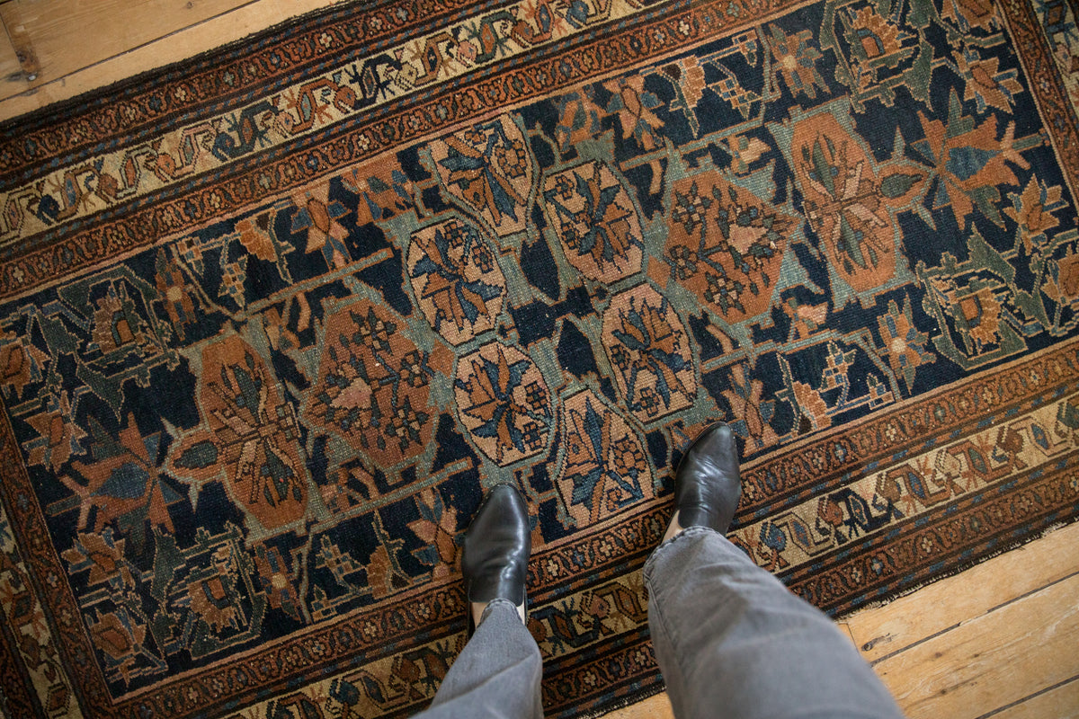 Vintage Persian Mehraban rug with angular arabesques and floral roundels in navy, rust, and dusty green tones.