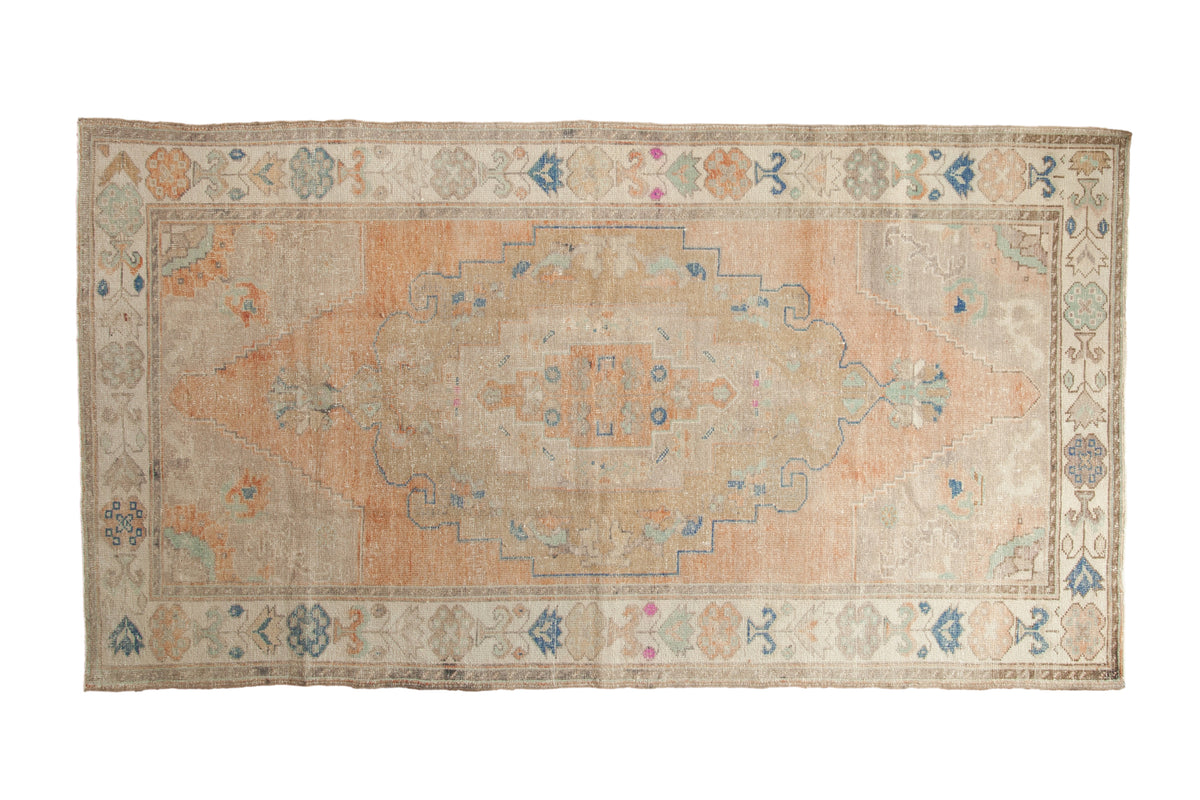 Hand knotted vintage distressed Oushak runner, faded peach medallion, beige field, blue motifs.
