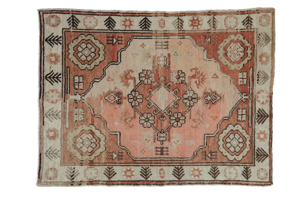 Vintage distressed Oushak rug with blush and copper tones, diamond medallion, and serrated motifs.