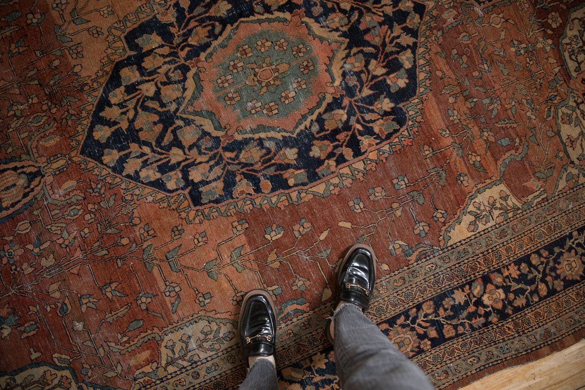 Antique Farahan Sarouk carpet's abrashed copper field, delicate vines, and navy arabesque spandrel.