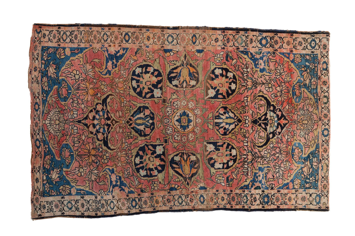 Antique Persian Farahan Sarouk rug with blush field, navy central medallion, and sprawling floral motifs.