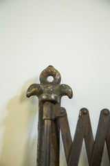 Close-up of the antique mirror's darkened fleur de lis mounting hardware and accordion arm.