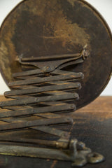 Darkened patina on the rusted metal accordion mechanism of the antique shaving mirror.
