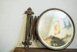 Antique accordion shaving mirror with its darkened frame, aged folding arm, and fleur de lis bracket.