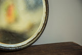 Close-up of the antique shaving mirror's beveled glass edge with aged patina and markings.