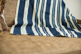Draped vintage indigo stripe throw with hand woven texture in blue and off-white.