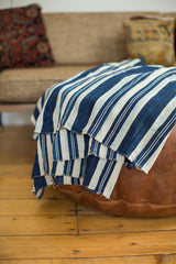 Folded layers of the vintage indigo stripe throw, highlighting its hand-woven texture and raw edges.