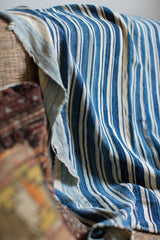 Frayed edge and hand-woven texture of a vintage indigo striped cotton throw.