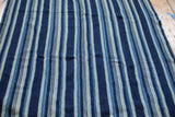 Intricate hand-woven texture with varied indigo blue stripes on the vintage textile.