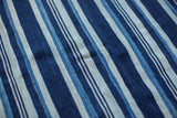 Hand-woven indigo striped textile detail showcasing intricate texture and faded blue variations.