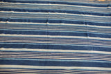 Close-up of hand woven cotton textile with variegated indigo and off-white stripes.