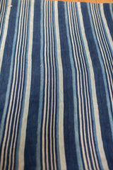 Vintage indigo textile with hand-woven striped texture and subtle variations in blue tones.