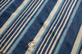 Hand woven indigo blue striped textile detail, with varied tones and aged texture.