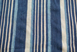 Close-up of the hand woven vintage indigo textile's varied blue and cream stripes.