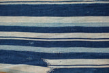Handwoven indigo striped African textile with varying blue tones and a storied repair.