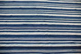 Hand-woven indigo textile with varied blue and white horizontal stripes.