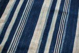 Hand-woven indigo blue textile close-up showing varied striped patterns and subtle dye texture.