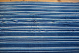 Hand woven vintage indigo textile with varying blue stripes and natural texture.