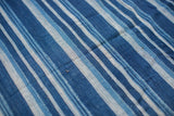 Handwoven texture visible in varied indigo blue stripes on a vintage cotton textile.
