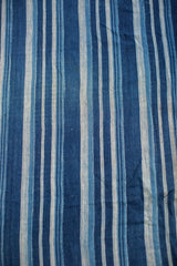 Visible texture of hand-woven vintage cotton textile with varied indigo blue stripes.