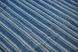 Textured close-up of vintage hand-dyed indigo striped textile with natural woven character.