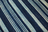 Close-up of collectible hand-woven indigo textile, featuring striped pattern and nuanced blue tones.